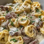 Philly Cheesesteak Tortellini Pasta with steak bites, cheese tortellini, and creamy provolone sauce, topped with fresh herbs in a shallow bowl.