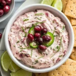 Cranberry Jalapeño Dip Costco copycat made with cream cheese, fresh cranberries, jalapeños, and herbs, served with crackers and lime wedges.