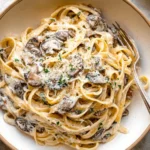 Creamy Mushroom Cream Sauce Pasta with fettuccine, sautéed mushrooms, Parmesan, and parsley in a rustic bowl.
