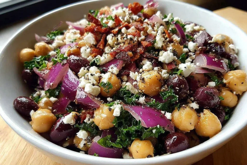 Divorce Salad in a white bowl with chickpeas, black beans, red onion, feta, parsley, and a tangy olive oil vinaigrette
