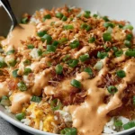 Chicken Crispy Rice Salad with Peanut Dressing in a white bowl with golden crispy rice, creamy peanut drizzle, and sliced green onions.