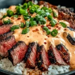 Korean BBQ Steak Rice Bowls with sliced grilled steak over fluffy rice, drenched in spicy cream sauce and topped with green onions and chili flakes.