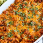 Chicken and Rice Queso Casserole baked golden with melty cheese, taco-seasoned chicken, and cilantro in a white casserole dish.