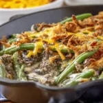 Ground Beef Casserole with Green Beans in a skillet with creamy sauce, melted cheese, mushrooms, and crispy onion topping.