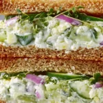 Cucumber Salad Sandwiches on whole-grain bread with creamy Greek yogurt, feta, fresh herbs, sprouts, and red onion slices.