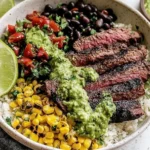 Cilantro Lime Steak Bowls with sliced grilled flank steak, cilantro-lime sauce, black beans, charred corn, pico, and rice with lime wedge.