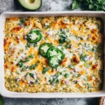 Salsa Verde Chicken Casserole baked in a white dish with melted cheese, salsa verde sauce, jalapeño slices, cilantro, and diced red onion.
