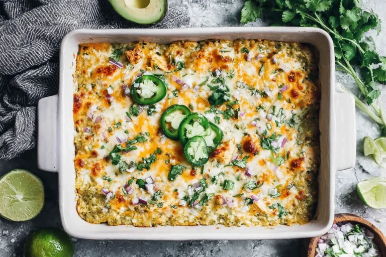 Salsa Verde Chicken Casserole baked in a white dish with melted cheese, salsa verde sauce, jalapeño slices, cilantro, and diced red onion.