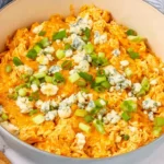 Buffalo Chicken Casserole in a white skillet, creamy and cheesy with blue cheese crumbles and green onions on top.