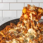 Chicken Parmesan Gnocchi pulled from a skillet with gooey mozzarella cheese stretch, marinara sauce, tender chicken, and a crispy Parmesan breadcrumb topping.