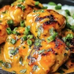 Low Carb Bang Bang Chicken in a skillet, coated in creamy spicy sauce and topped with chopped green onions, served over cauliflower rice.