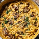 Creamy Mushroom and Spinach Orzo in a Dutch oven, with sautéed cremini mushrooms, wilted spinach, and a creamy Parmesan sauce.