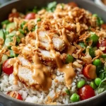 Chicken Crispy Rice Salad with Creamy Peanut Dressing topped with crispy chicken, jasmine rice, cucumbers, cherry tomatoes, herbs, and peanut sauce.