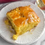 Honey Butter Cornbread square on a plate, drizzled with glossy honey butter, showing a moist, tender crumb.