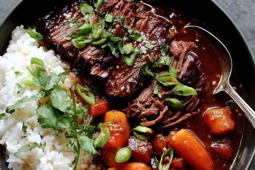 Korean Style Pot Roast in a bowl with steamed white rice, gochujang-braised shredded beef, carrots, and scallions with cilantro.