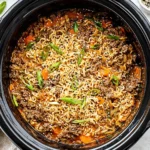 Slow Cooker Ramen Noodles with Ground Beef cooking in a black crockpot with carrots, sesame seeds, and green onions.