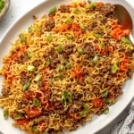 Slow Cooker Ramen Noodles with Ground Beef topped with green onions, served on a white plate for an easy weeknight dinner.