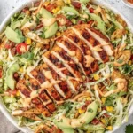 Spicy Ranch Chopped Chicken Cabbage Salad in a bowl with grilled sliced chicken, avocado, corn, jalapeño, cilantro, and tortilla strips.