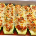 Keto Chicken Parmesan Zucchini Boats in a baking dish, stuffed with saucy ground chicken and topped with golden melted mozzarella and parmesan.