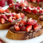 Chocolate Strawberry Bruschetta on toasted sourdough with creamy Nutella spread, diced strawberries, and a sprinkle of crunchy walnuts.