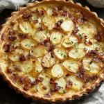 Creamy Irish Potato Pie in a flaky puff pastry crust, topped with sliced potatoes, crispy bacon, and fresh herbs, baked until golden.