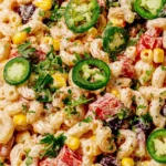 Close-up of Mexican Macaroni Salad with creamy lime dressing, black beans, corn, red peppers, cilantro, and sliced jalapeños.
