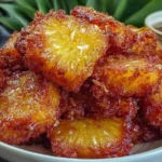 Air Fryer Pineapple Chunks stacked in a bowl, deeply caramelized and glossy with crisp edges, served with a sweet dipping sauce.
