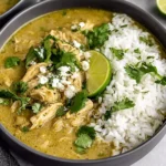 Bowl of Crockpot Chicken Chili Verde with shredded chicken in salsa verde sauce, served with white rice, cilantro, and a lime wedge.