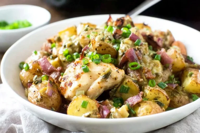 German Fried Potatoes with Chicken in a white bowl—crispy red potatoes, tender chicken, turkey bacon, and green onions in a tangy skillet sauce.
