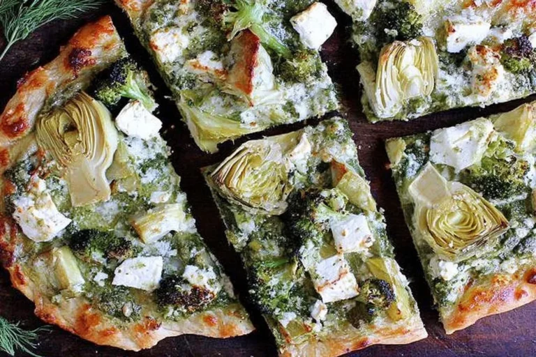 Green Pizza with Pesto, Feta, Artichokes, and Broccoli sliced into wedges with creamy feta, tender artichokes, and pesto on a golden crust.