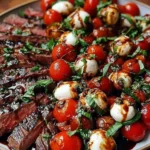 Grilled Flank Steak Caprese served with sliced grilled flank steak, cherry tomatoes, mozzarella pearls, fresh basil, and balsamic glaze on a platter.