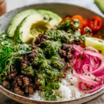 Ground Beef Chimichurri Bowls piled over fluffy rice with chimichurri-drizzled ground beef, sliced avocado, pickled red onions, fresh herbs, and lime.