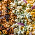 High-Protein Chicken Street Corn Salad in a bowl with grilled chili-lime chicken, charred corn, red onion, herbs, and crumbled cotija cheese.