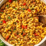 Creamy Taco Mac and Cheese in a skillet with lean ground beef, elbow pasta, red bell pepper, and cilantro.