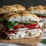 Italian Turkey Focaccia Sandwiches on herbed focaccia rolls with sliced turkey, prosciutto, mozzarella, sun-dried tomatoes, and fresh greens.