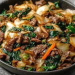 Keto Beef and Cabbage Stir-Fry in a skillet with tender beef slices, sautéed cabbage, onions, and greens in a savory soy-ginger sauce.