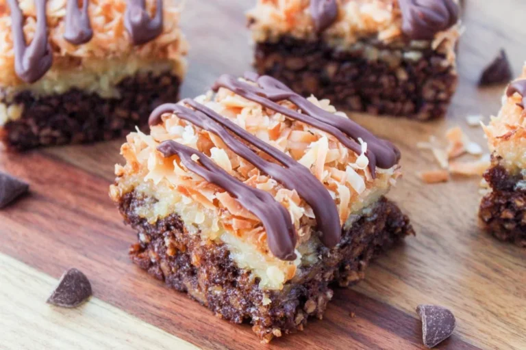Samoa Brownies with fudgy chocolate base, toasted coconut caramel layer, and chocolate drizzle on a wooden board.