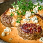 Keto Feta Burgers With Tomato Cream Sauce in a skillet, topped with feta crumbles and fresh herbs in a creamy tomato-feta sauce.