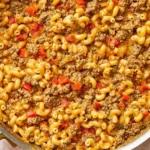 Close-up skillet of Taco Mac and Cheese with seasoned ground beef, cheesy elbow pasta, and diced red bell peppers.
