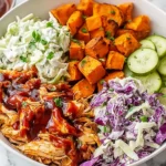 BBQ Chicken Bowls with Sweet Potatoes, Coleslaw, and Pickles featuring saucy shredded BBQ chicken, roasted sweet potatoes, creamy slaw, and fresh cucumber slices.
