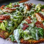 Chicken Crust Caesar Salad Pizza with crispy romaine, grated Parmesan, creamy Caesar drizzle, and crunchy chicken bacon bits on a golden chicken crust.