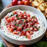Boursin Bruschetta Dip in a bowl topped with chopped tomatoes, fresh basil, and pepper, served with toasted crostini.