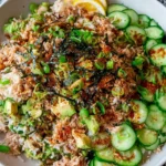 Tuna Avocado Crispy Rice Salad in a bowl with cucumber slices, flaky tuna, diced avocado, scallions, and seaweed on rice
