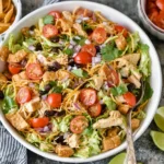 Taco Chicken Salad with romaine lettuce, shredded chicken, black beans, cherry tomatoes, cheddar, cilantro, and crunchy tortilla strips with fresh lime.