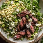 Grilled Skirt Steak with Lemon Herb Couscous Salad served in a rustic bowl with Israeli couscous, cucumber, arugula, fresh herbs, and crumbled feta.