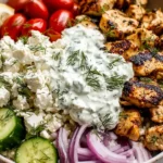 High Protein Mediterranean Lemon Dill Chicken Bowl with charred lemon-dill chicken, creamy tzatziki, feta, cucumbers, tomatoes, and red onion over rice.