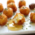Crispy Goat Cheese Poppers with Honey being drizzled with honey, showing a creamy melted center and crispy golden panko crust on a serving board.