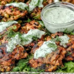Mediterranean Grilled Chicken Thighs topped with creamy dill yogurt sauce on a platter with fresh dill and greens.
