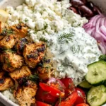 High Protein Mediterranean Lemon Dill Chicken Bowl with grilled lemon-dill chicken, creamy tzatziki, cucumber, tomatoes, feta, red onion, and olives.