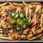 Smash Burger Fries piled on crispy fries with seasoned ground beef, melted cheddar cheese, special sauce drizzle, and jalapeños with tomatoes.